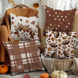 Set of 4 fall pillow covers with football and maple leaf patterns on a cozy sofa