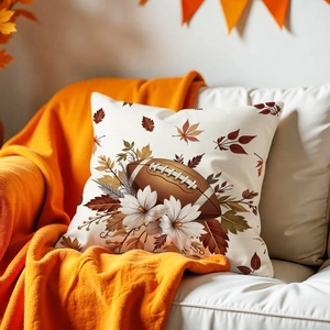 Detail of vintage maple leaf and rugby pillow cover on a white leather sofa with a blanket