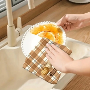 Close-up of microfiber dish towel with pumpkin print cleaning oil off a ceramic plate