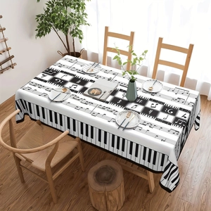 Detail of music-themed tablecloth showing piano keys and musical notes on wood table