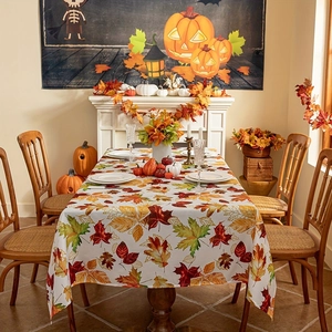 Detail of autumn maple leaf pattern tablecloth with festive pumpkins and fall decor