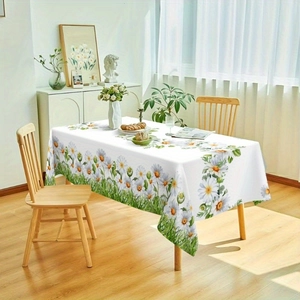 Detailed close-up of a white rectangular tablecloth featuring daisy and grass prints