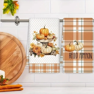 Detail view of two microfiber autumn kitchen towels with pumpkin prints and HELLO PUMPKIN text