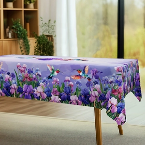 Detail of purple tablecloth featuring iris flowers and hummingbirds in natural setting