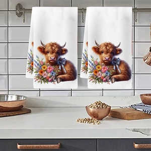 Detail of two white kitchen towels featuring highland cow prints hanging in a kitchen decor