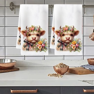 Macro shot of hanging kitchen towels featuring floral highland cow print on white fabric