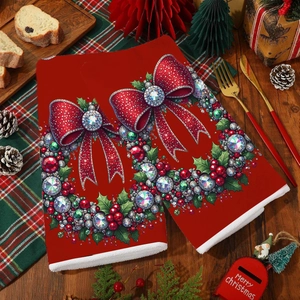 Macro detail of red Christmas kitchen towel featuring gemstone bow and festive wreath design
