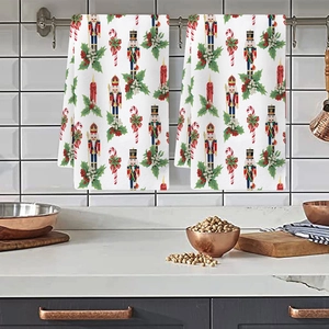 Detail view of two Christmas kitchen towels featuring nutcracker and holiday patterns