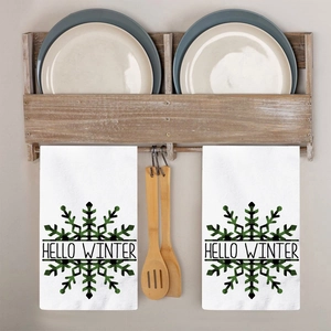 Detail of Hello Winter snowflake tea towels hanging on a wooden rack in a warm kitchen