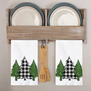 Detail showing two white kitchen towels with green fir trees and black buffalo plaid pattern