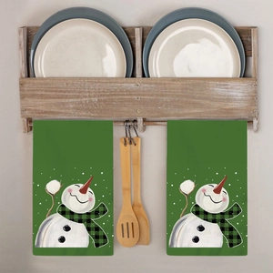 Detail view of two green Christmas snowman kitchen towels hanging on a rustic wooden rack