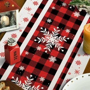 Detail van rood-zwarte geruite kersttafelloper met decoratieve sneeuwvlokken-print