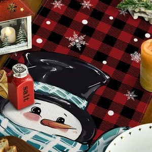 Detail van kersttafelmat met sneeuwpop print en rood zwart buffel ruitpatroon ontwerp