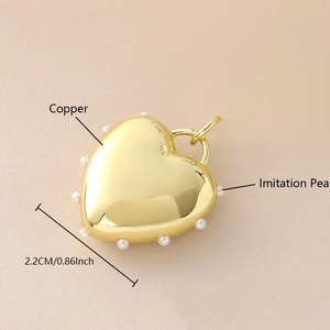 Vista macro de un colgante de corazón de 2,2 cm en cobre bañado en oro y perlas blancas