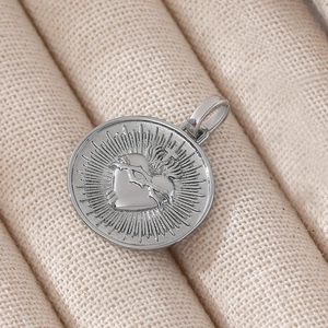 Ciondolo cuore sacro in argento lucido con croce e spine su vassoio in tessuto beige