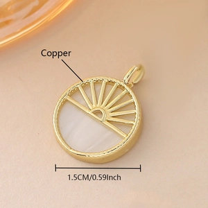 Detalle de un colgante circular de cobre dorado de 1,5 cm con nácar y motivo de sol