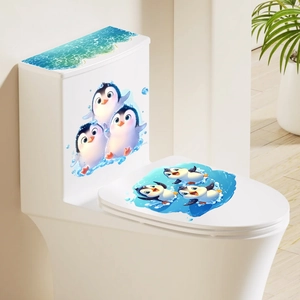 Detail of 3D cartoon penguin stickers and blue ocean waves on a white modern toilet seat