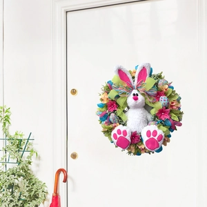 Easter bunny wreath decoration with pink flowers and green bow on a white wooden door
