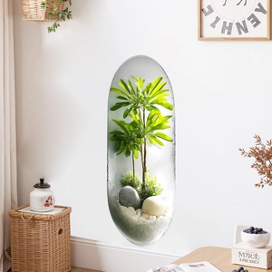 Capsule shaped wall mounted glass planter with green plants and decorative pebbles