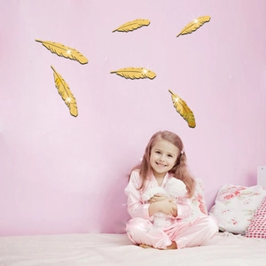 Detail of golden feather acrylic mirror wall stickers in a cozy bedroom setting
