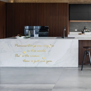 Close-up of golden acrylic mirror wall sticker with quote on white marble island