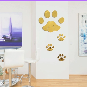 Detail of four golden acrylic mirror paw print wall stickers on a modern white column