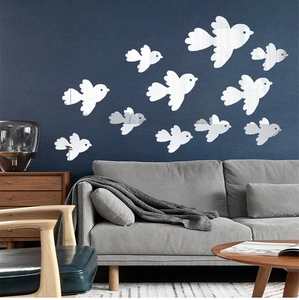 Modern acrylic bird mirror wall stickers displayed above a gray sofa in a living room