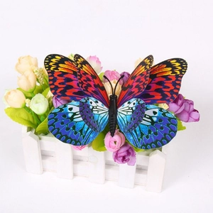 Détail du décor papillon 3D double couche aux ailes rouge et bleu sur une clôture blanche