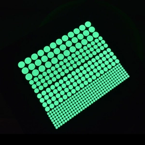 Luminous green dot wall stickers in various sizes glowing on a dark background