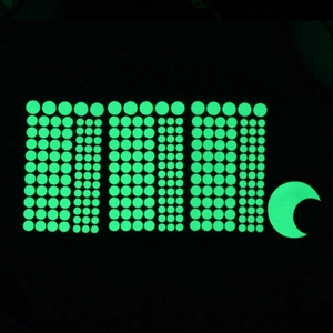 Luminous wall stickers set with dots and moon glowing in green on dark background