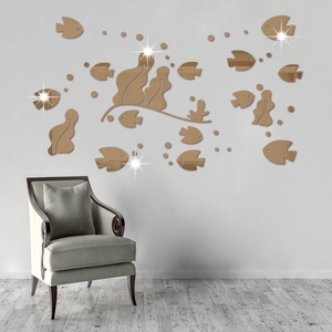 Detail view of gold acrylic fish mirror wall stickers on a white wall above a sofa