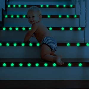 Luminous star stickers glowing bright green on indoor stairs with a crawling toddler