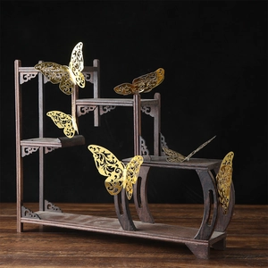 Elegant 3D golden metal butterfly wall stickers on a dark wood tiered display stand