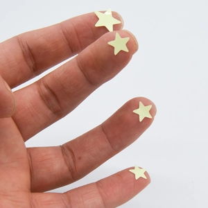 Macro detail of tiny glow-in-the-dark star stickers on fingertips for size comparison