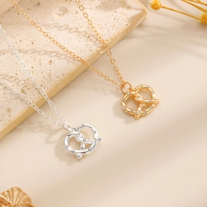 Dettaglio delle collane a bretzel in oro e argento con ciondoli con zirconi lucidi