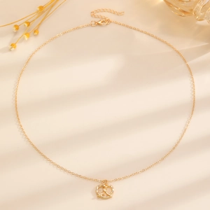 Collana con ciondolo a pretzel dorato con zirconi in un ambiente elegante