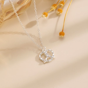 Dettaglio di una collana con ciondolo a nodo pretzel in argento con zirconi brillanti
