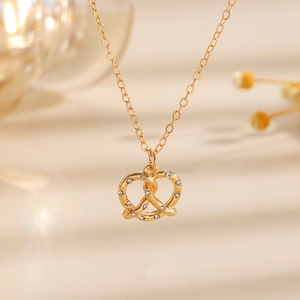 Dettaglio macro del ciondolo a pretzel dorato con zirconi brillanti su catena sottile