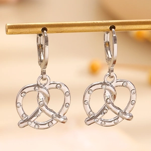 Dettaglio macro di orecchini a forma di pretzel con zirconi su supporto dorato