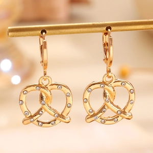 Dettaglio ravvicinato di orecchini a forma di pretzel dorati con zirconi brillanti