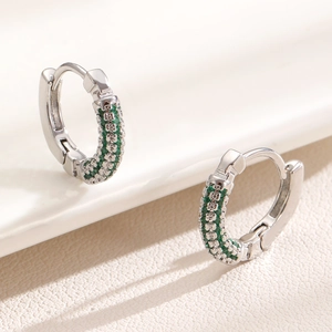 Macro shot of silver huggie earrings with double-row micro-set green zircons