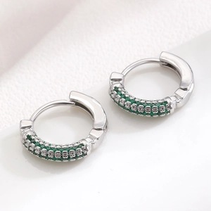 Macro shot of silver hoop earrings with triple rows of micro-paved green zircons