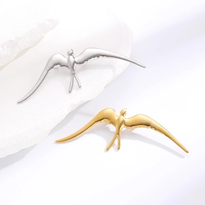 Détail macro de broches en forme d'oiseau en or et argent sur un support en pierre