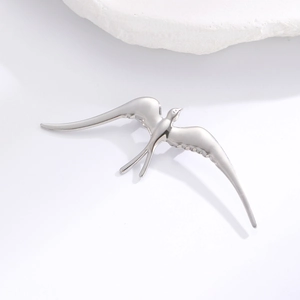 Détail macro d'une broche hirondelle en acier inoxydable poli avec textures d'ailes élégantes