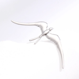 Détail macro d'une broche hirondelle en acier inoxydable poli au fini argenté