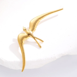 Broche élégante en forme d'hirondelle dorée présentée sur une pierre de marbre blanc