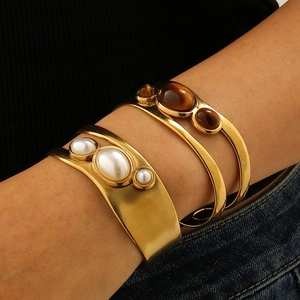 Detailed shot of 18k gold plated stainless steel cuff bracelets with tiger eye and pearls