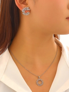 Detail of silver bridal jewelry set featuring leaf zircon earrings and pendant necklace