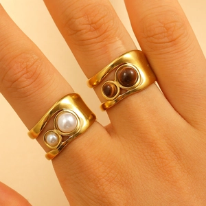 Detail of 18k gold plated open rings set with white pearl and brown tiger eye stones