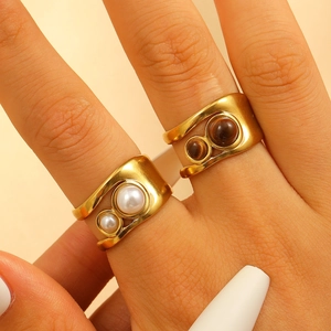 Detailed macro view of gold plated bangles with faux pearls and brown stones inserts